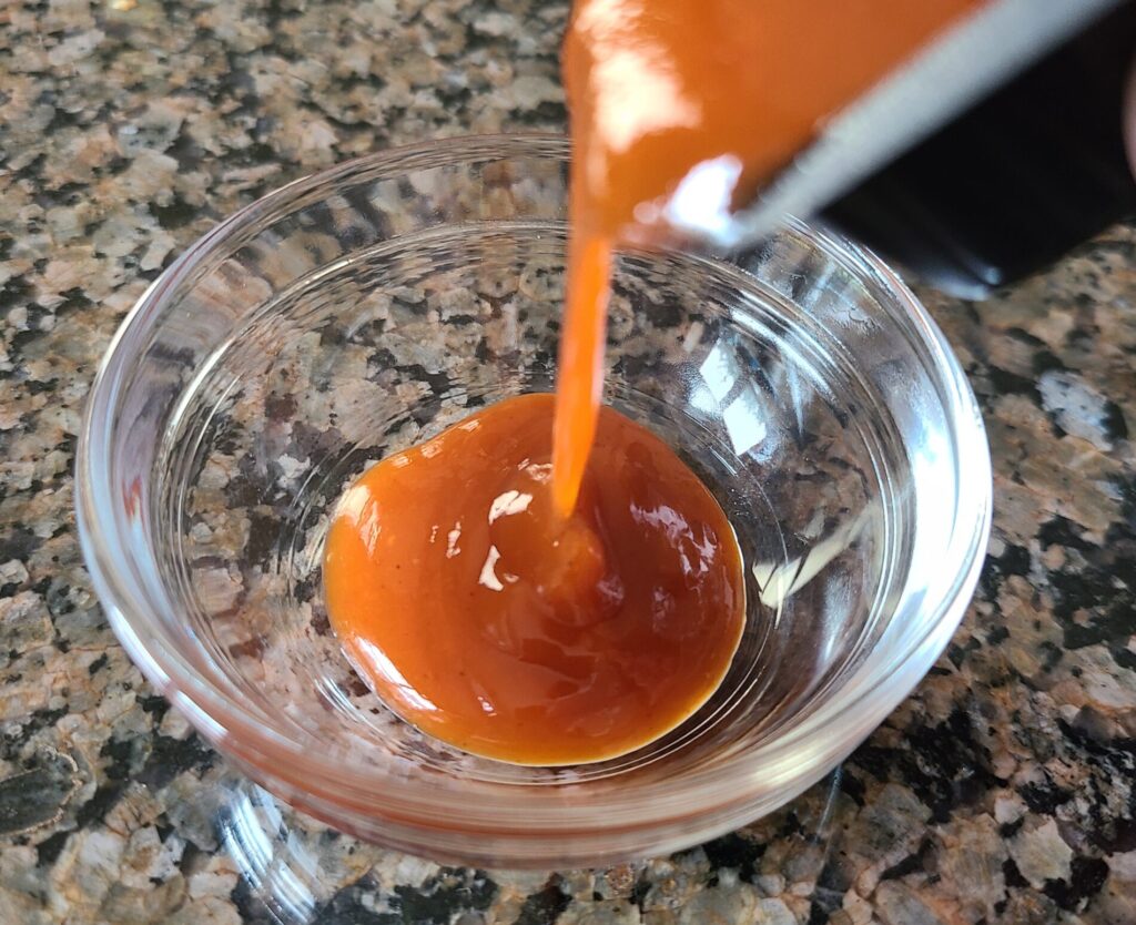 mighty hot sauce pouring into a dish